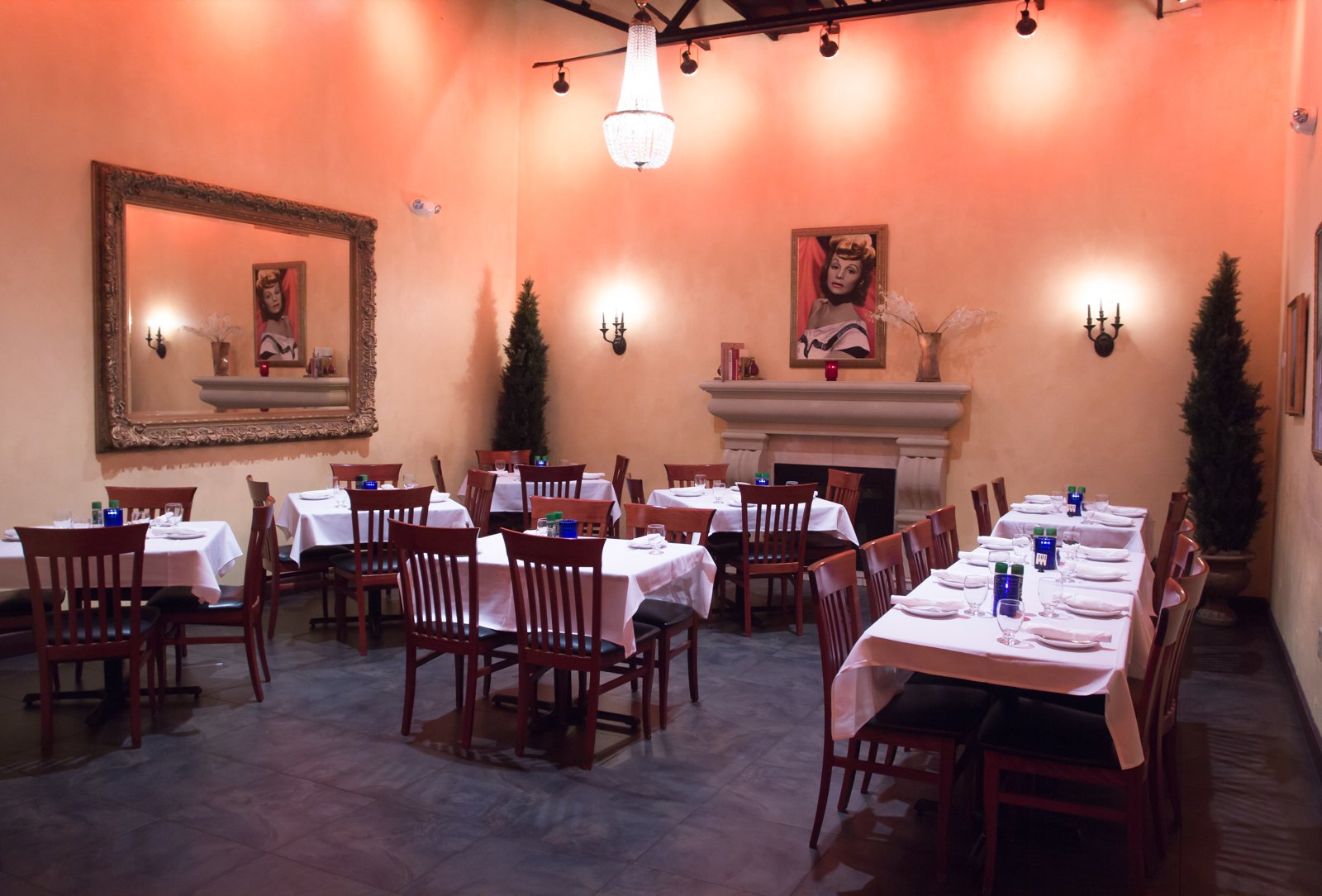 The private dining room at Visani in Port Charlotte, with white tablecloths, a fireplace, and a Lucille Ball portrait.